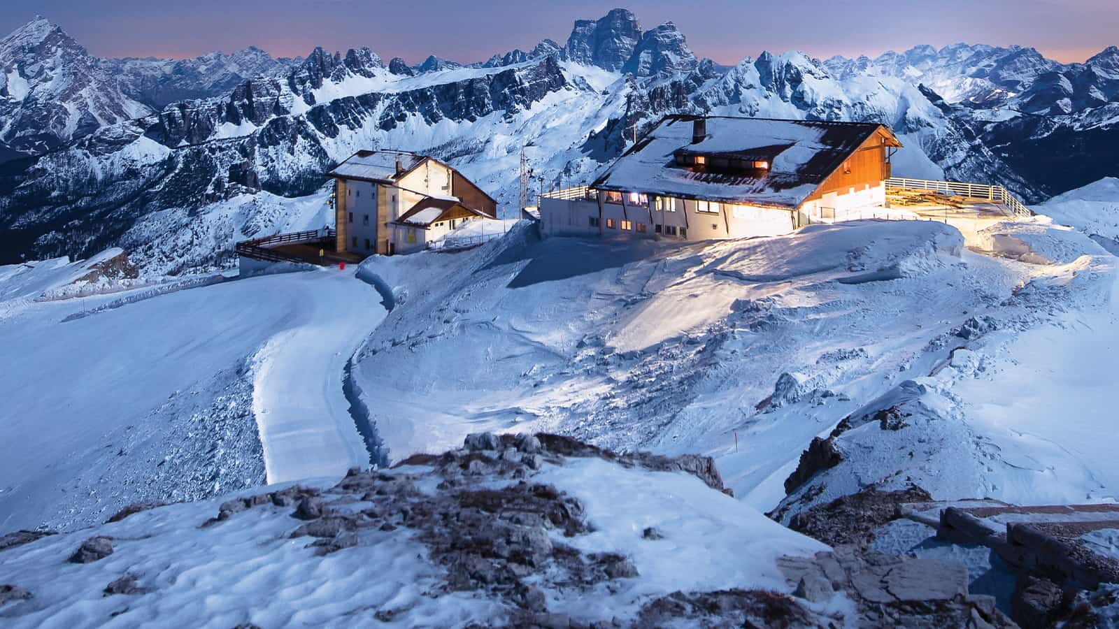 Cabañas en la cima de una alta montaña con las luces encendidas.