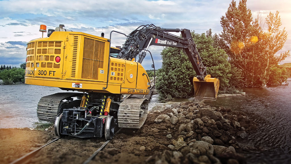 Un equipo de Brandt Rail Tool recoge rocas en un arroyo impulsado por un motor industrial John Deere.