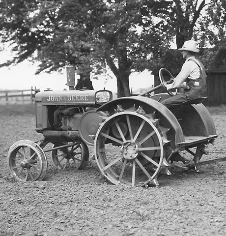 Tractor histórico John Deere de uso general "GP" tira de una azada giratoria John Deere n.° 7 en el campo