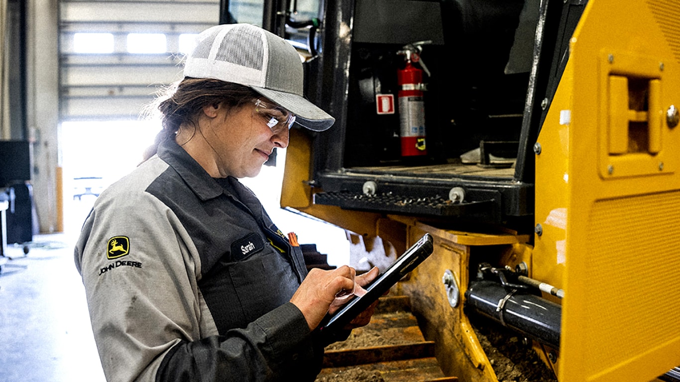 Un técnico de John Deere usa una tableta delante de un equipo