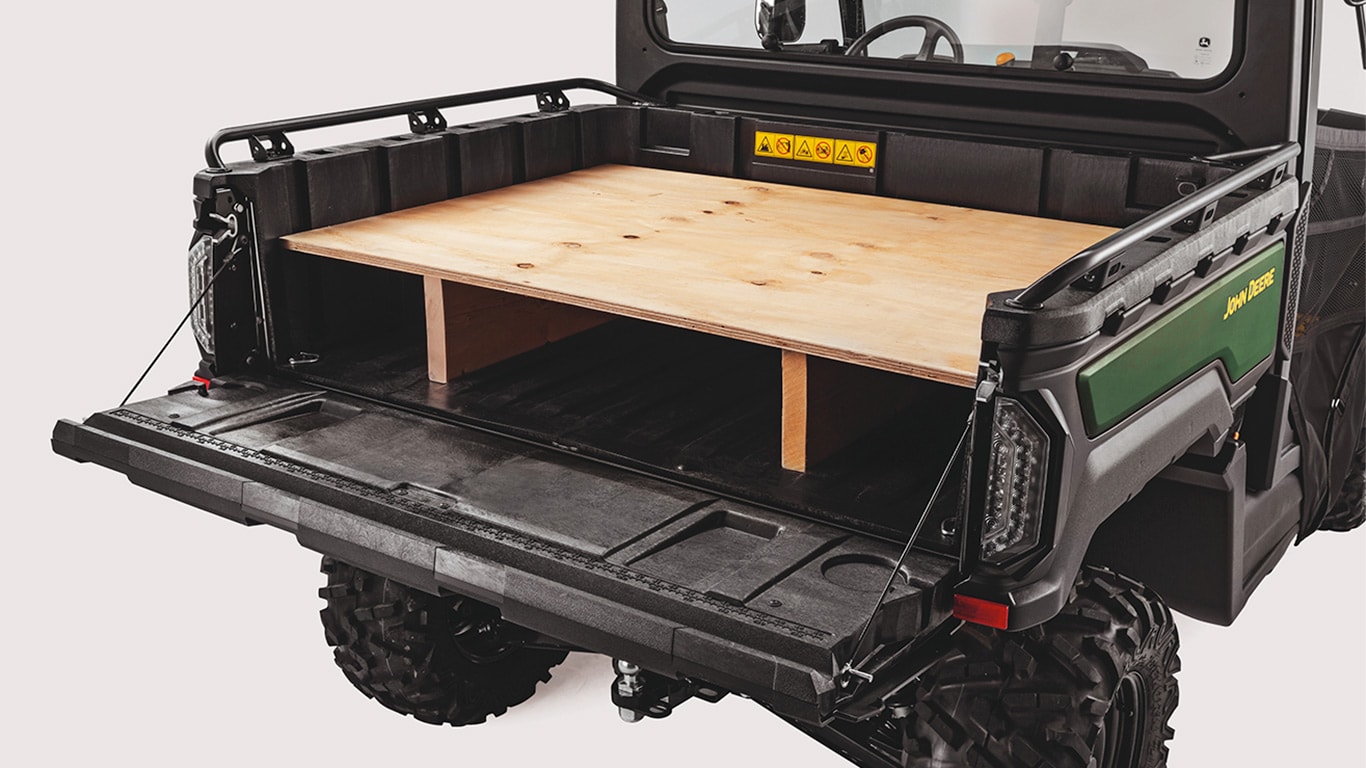 Portón trasero de un Gator™ XUV 875M plegado hacia abajo para utilizarlo como banco de trabajo