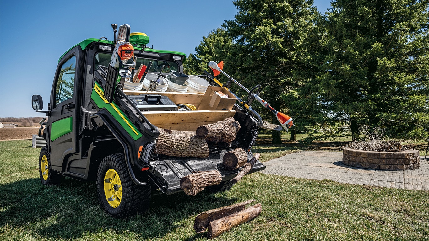 Gator™ XUV 875M descargando troncos de madera de la caja de transporte y almacenamiento