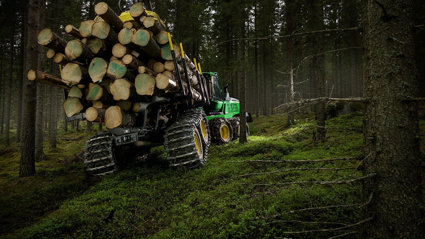El transportador de troncos 1510G de John Deere transporta troncos en el bosque