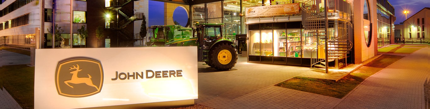 Vista de la fachada delantera del edificio de la sede de John Deere con estanque y sauces en primer plano