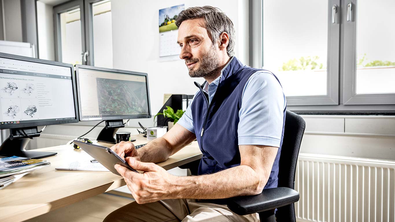 Un encargado jefe del mantenimiento de espacios verde utiliza su tableta en la oficina.