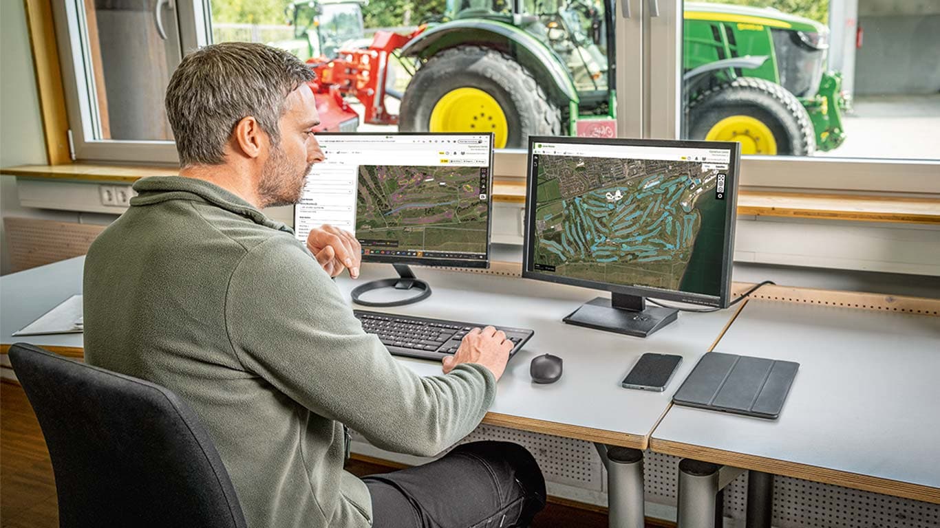 Un encargado jefe de mantenimiento observa los mapas de un campo de golf en su ordenador.