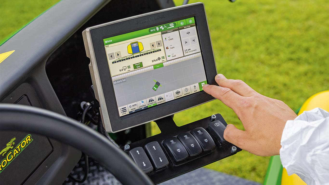 Un encargado del mantenimiento de los espacios verdes utiliza la pantalla de su segadora John Deere para ajustar la máquina a su tarea actual.
