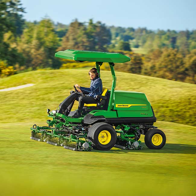 Un encargado del mantenimiento trabaja en una zona verde con una máquina de calles John Deere
