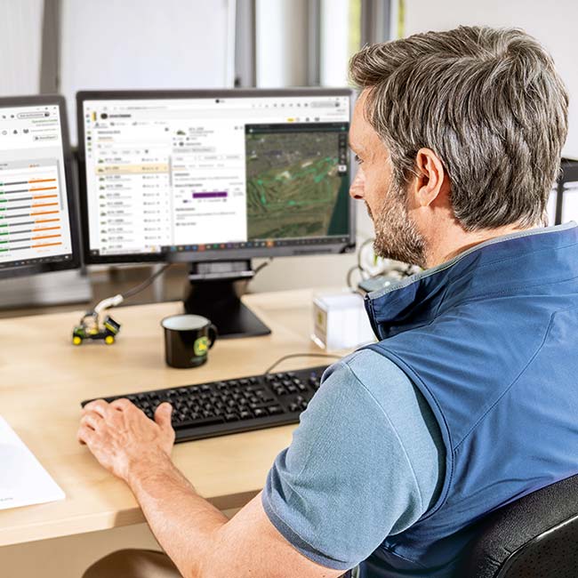 Un encargado jefe del mantenimiento se sienta en su oficina y observa los datos recopilados por la tecnología Smart Greenkeeping.