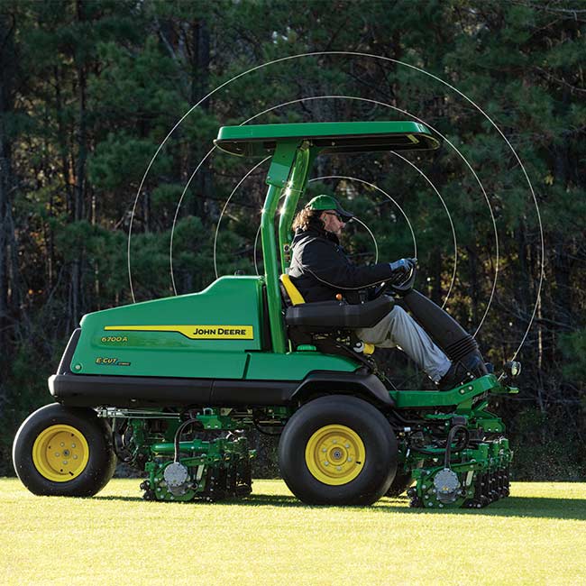 Un encargado del mantenimiento trabaja en una zona verde con una máquina de calles John Deere y utiliza tecnología de conectividad.